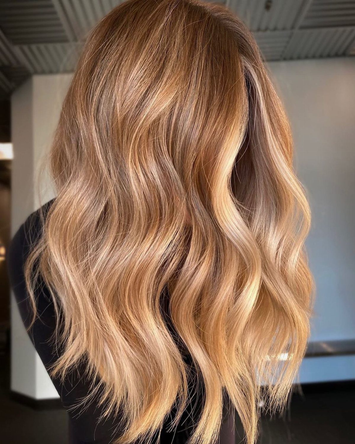 Wavy honey-blonde hair with golden highlights and darker roots