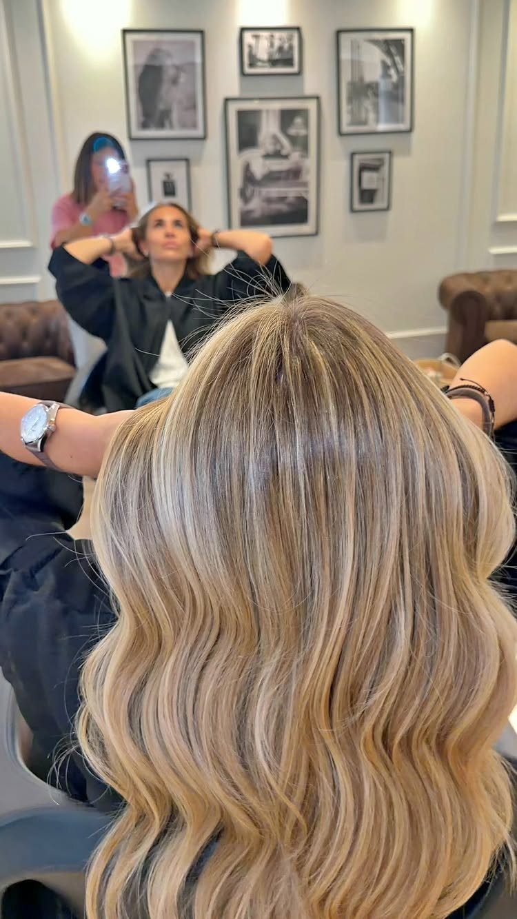 Wavy blonde balayage hair with darker roots and softly blended highlights