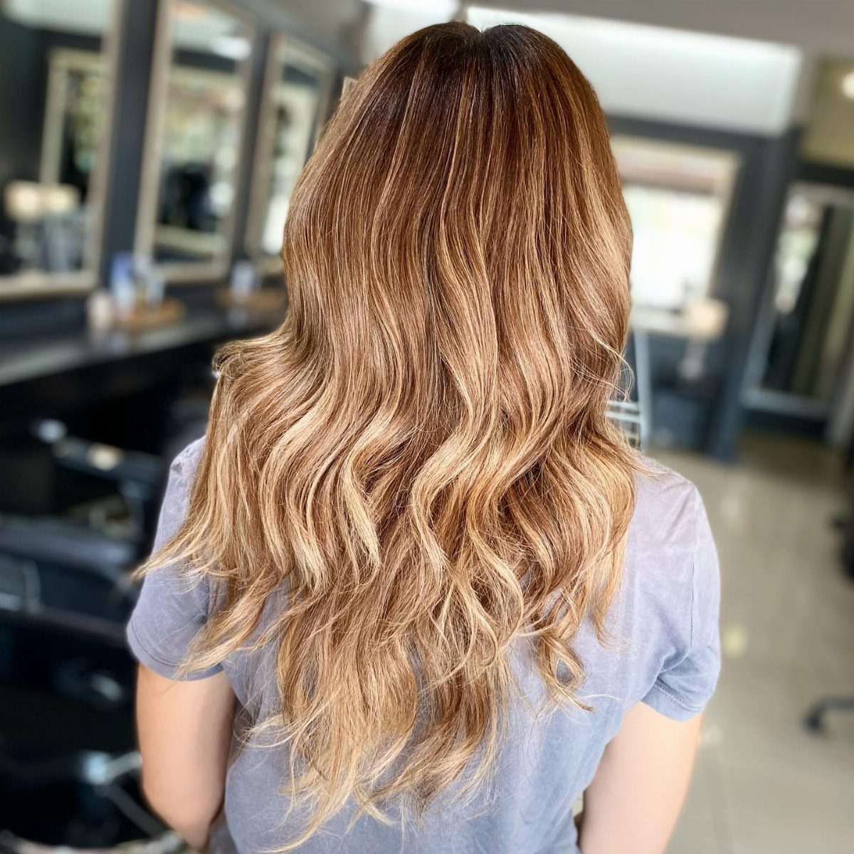 Long wavy brown-blonde hair with warm honey highlights in a salon