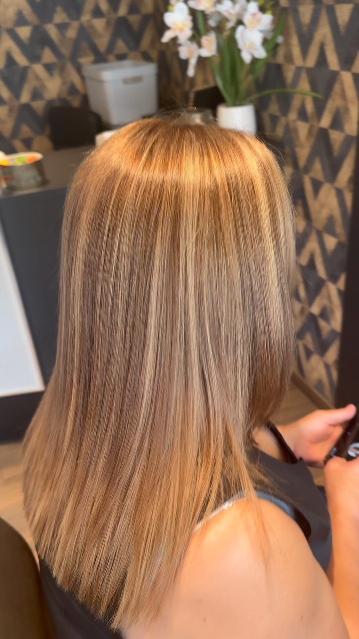 Long straight honey blonde hair with golden highlights in a salon