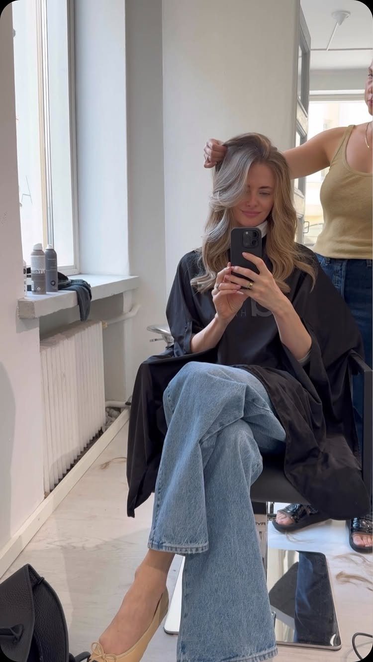 Woman with sandy blonde side-parted waves seated in a salon chair