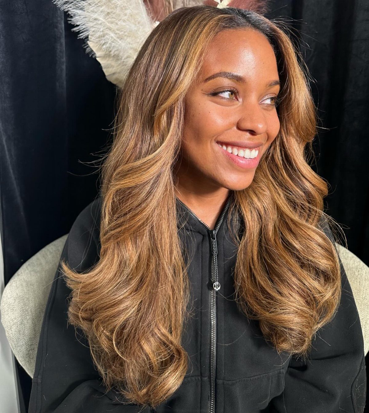Woman with long brown hair and broad honey-blonde face-framing highlights