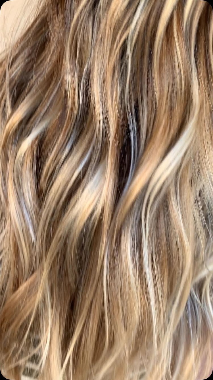 Long wavy blonde hair showing blended brown lowlights and dimensional balayage tones