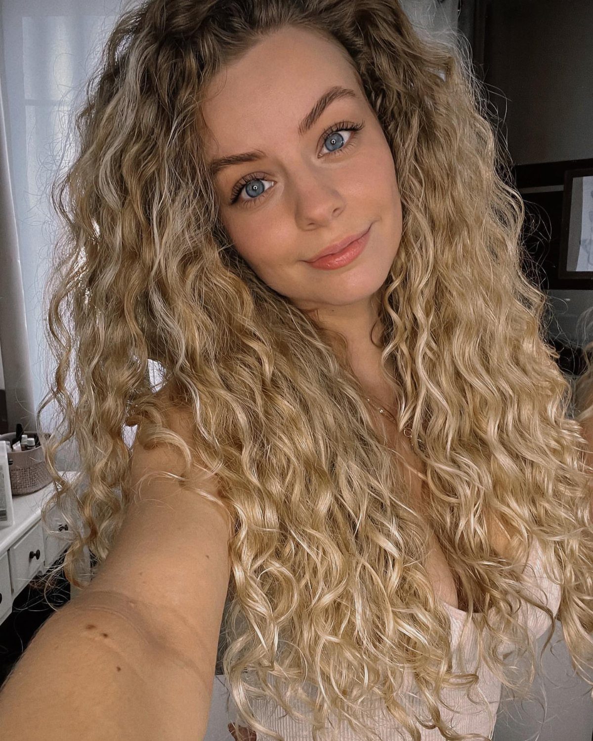 Woman with long blonde curls showing darker lowlights throughout