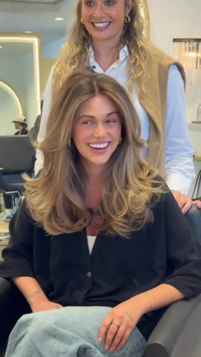 Woman with long blonde waves and visible dark lowlights in a salon