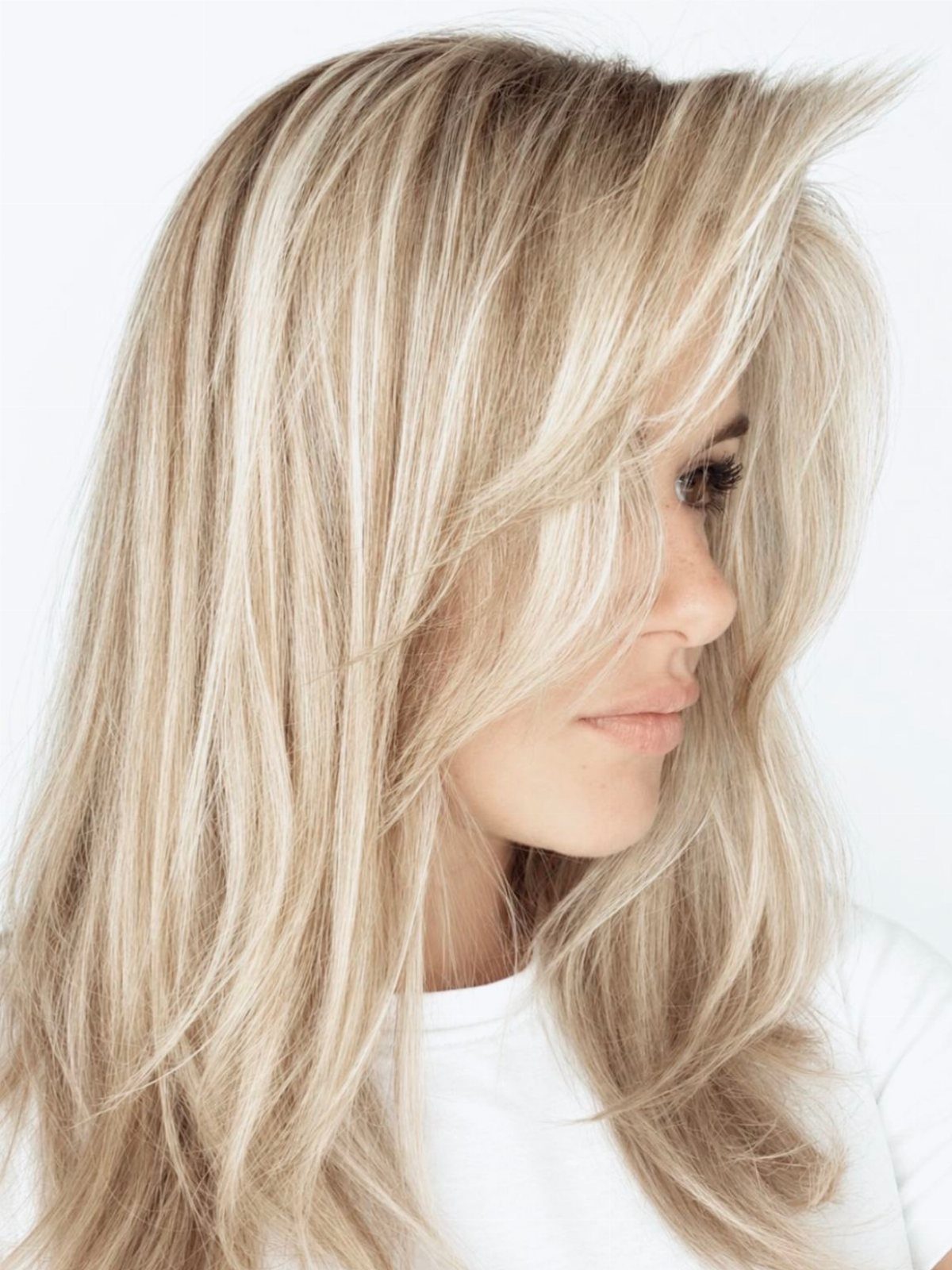 Long layered blonde hair with beige lowlights frames a woman's face