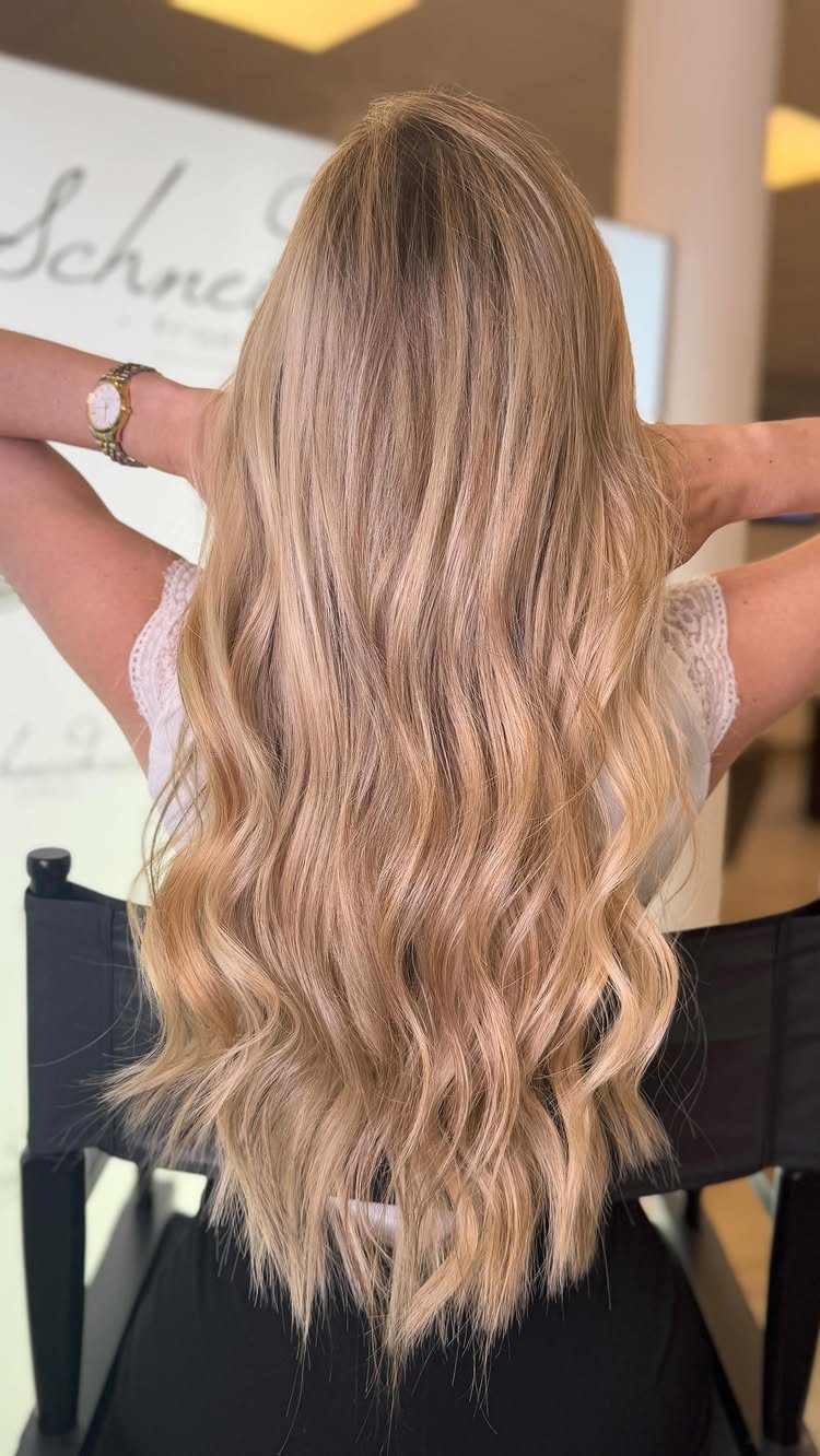 Long wavy blonde hair with blended highlights and lowlights in a salon