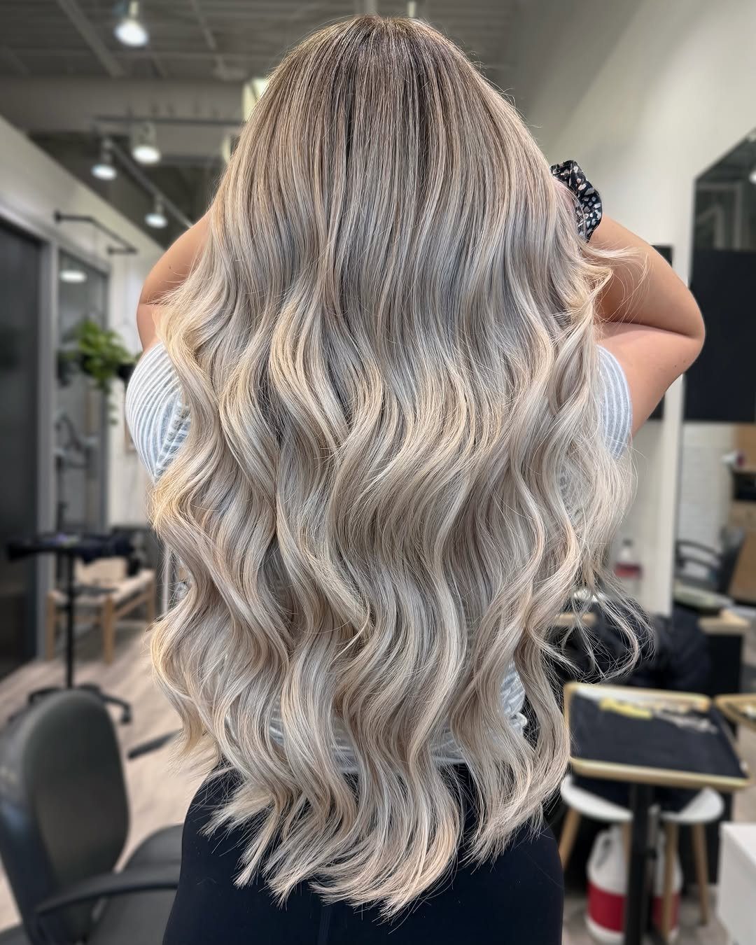 Long wavy blonde hair with blended dark roots and lowlights in a salon