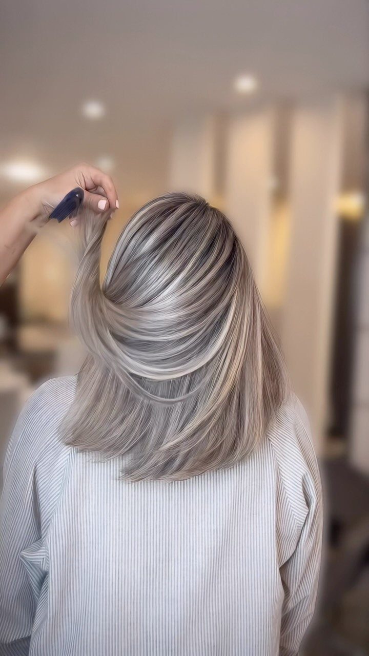 Shoulder-length blonde hair with darker lowlights styled smoothly in a salon