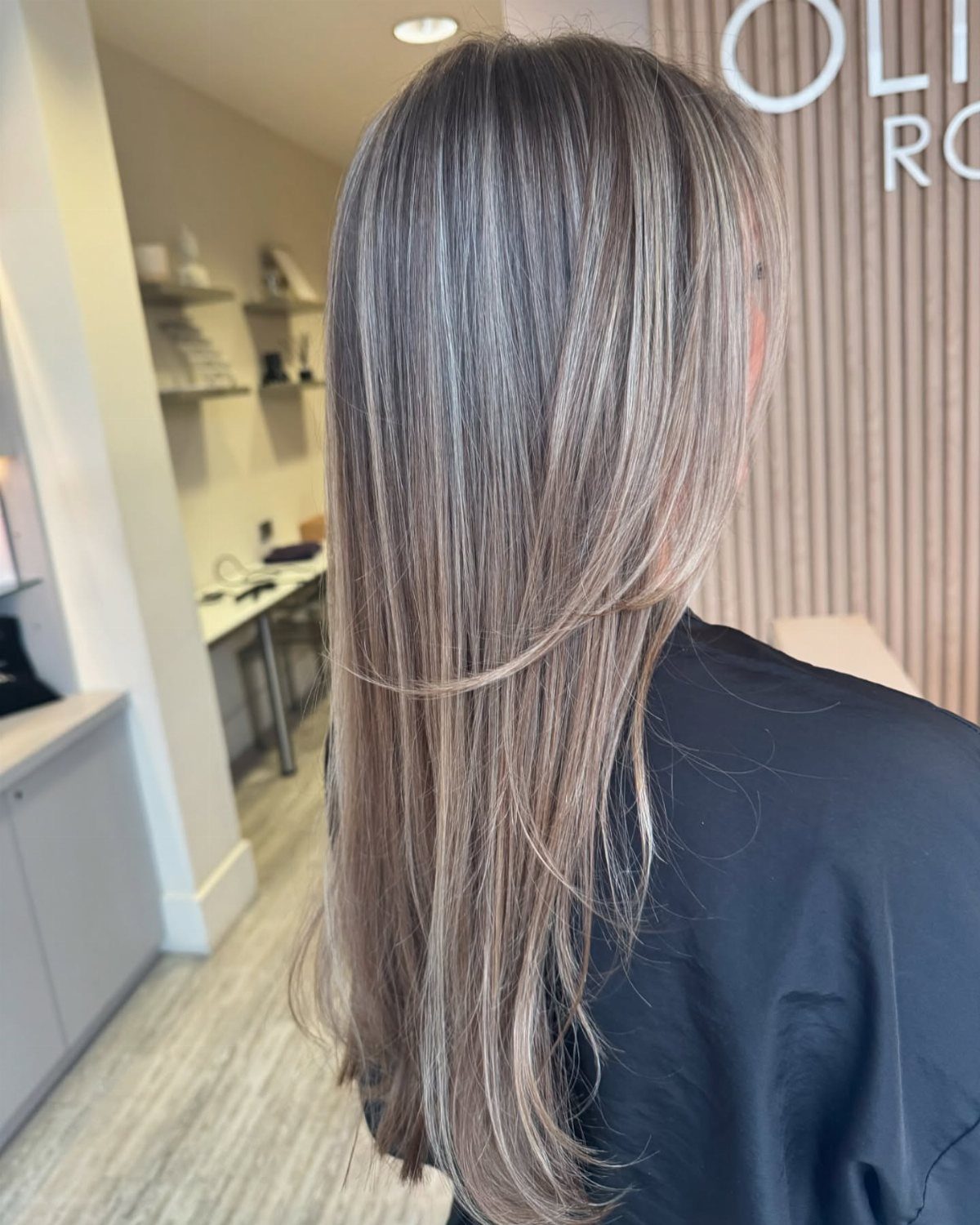 Long icy blonde hair with brunette lowlights shown from behind in a salon