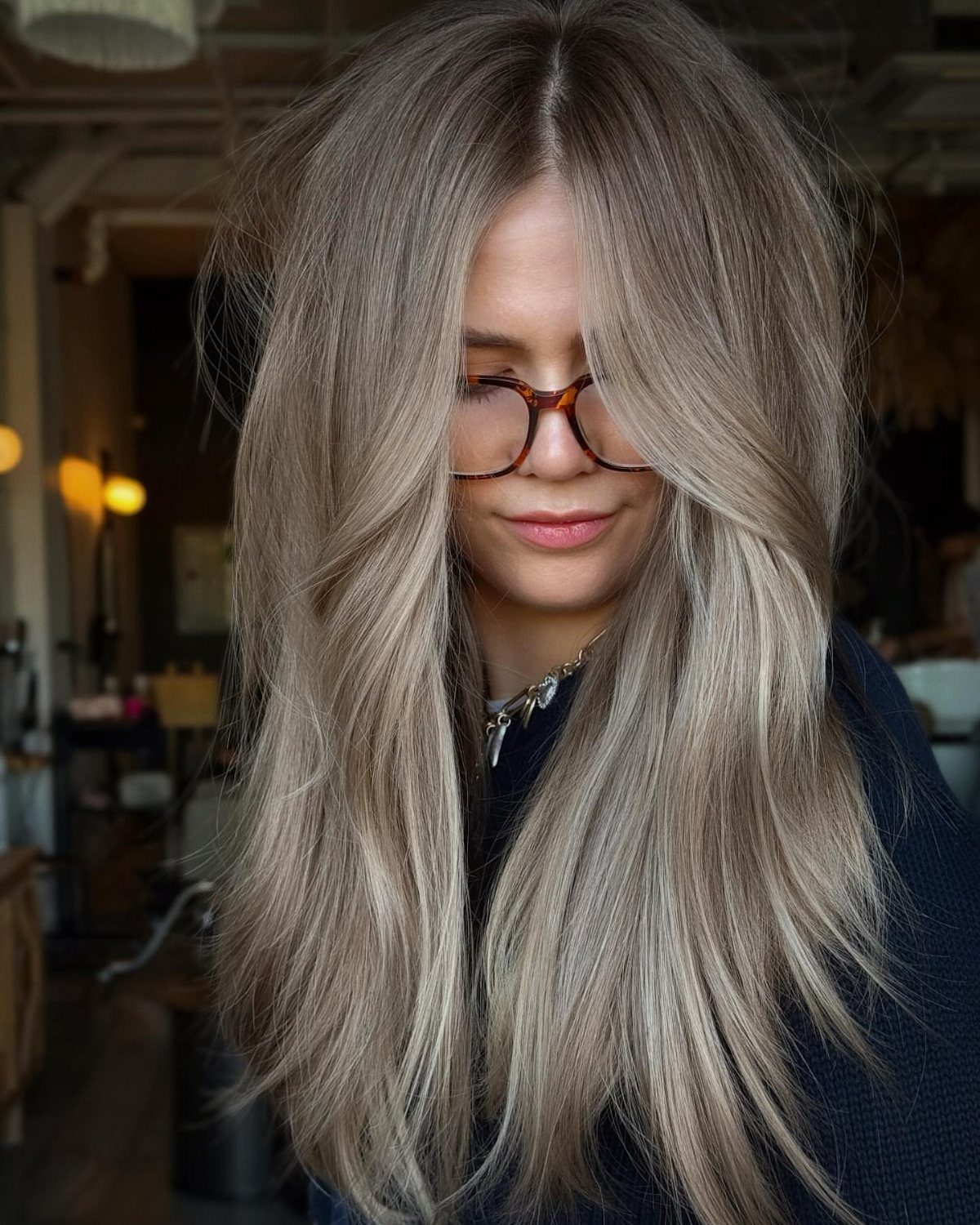 Woman with long straight ash-brown hair and pale blonde ribbons