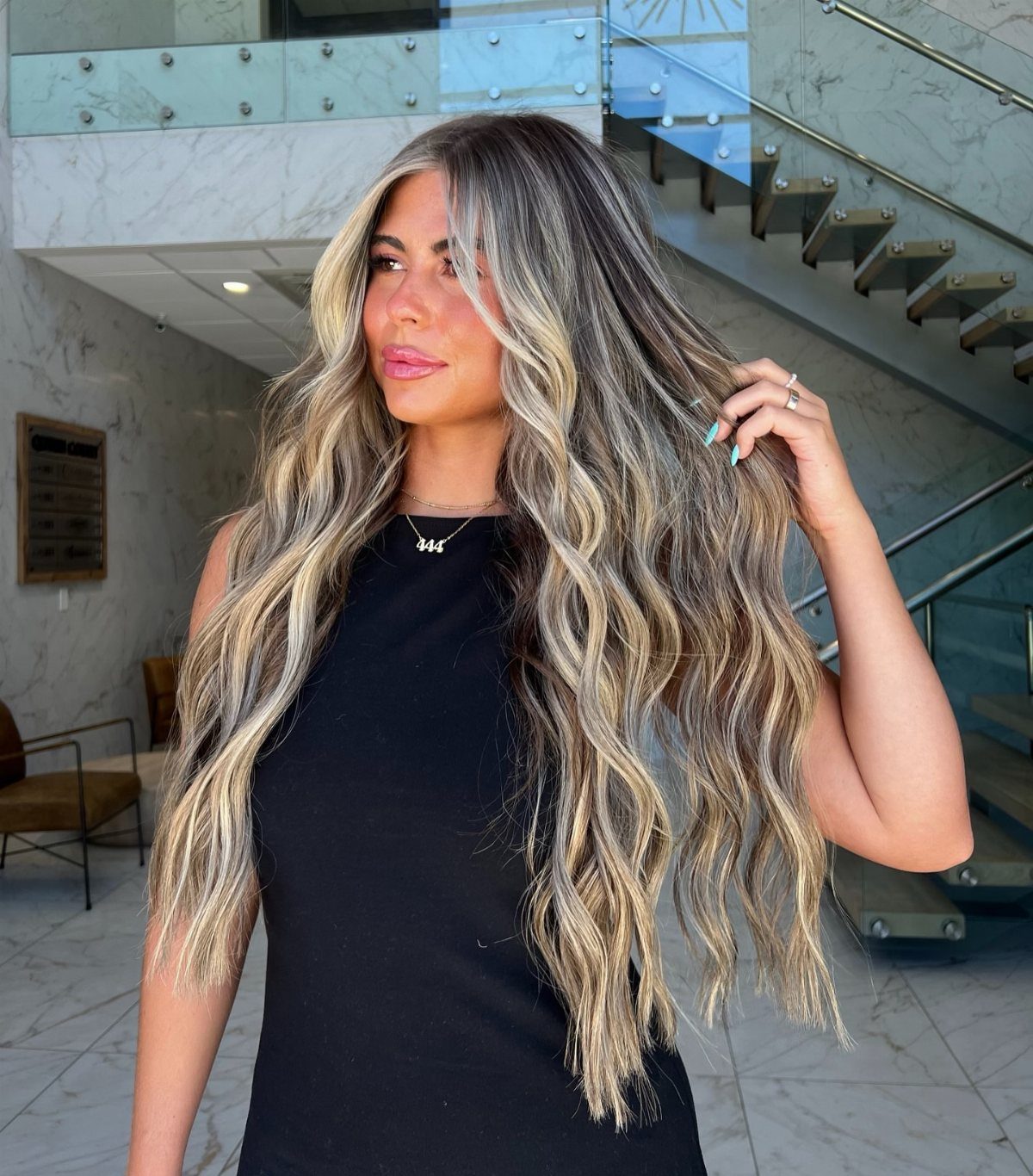 Woman displays long wavy brown hair with light blonde highlights