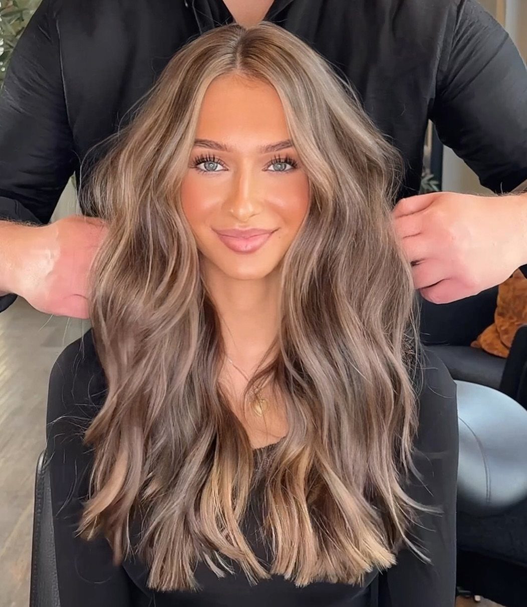 Woman displaying long brown hair with blended pale blonde highlights