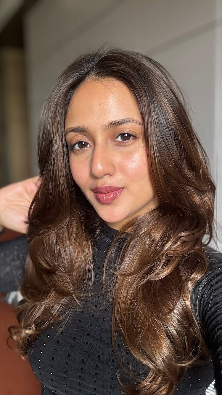 Woman with long wavy brown hair and warm caramel highlights