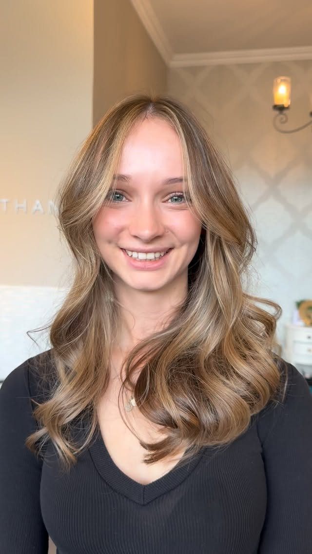 Woman with curled brown hair and blonde face-framing highlights
