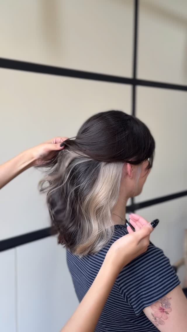 Woman holds dark brown hair with pale blonde sections at the ends