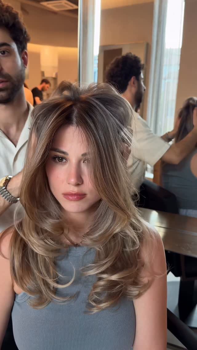 Woman with long light brown hair and sandy blonde highlights in a salon