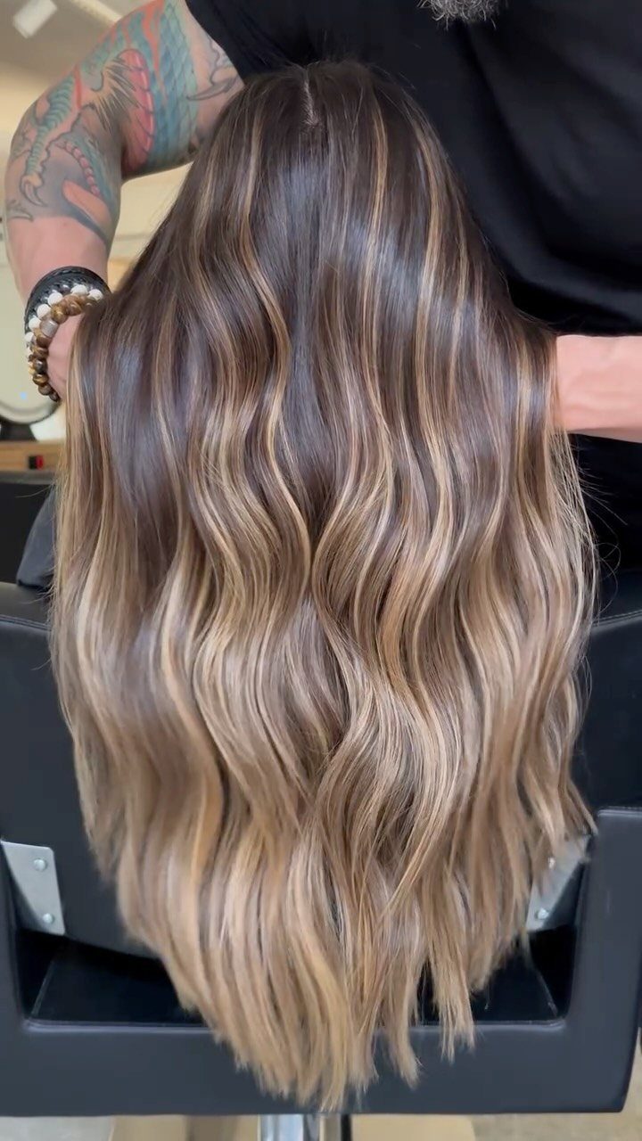 Long wavy brown hair with blended light blonde highlights in a salon