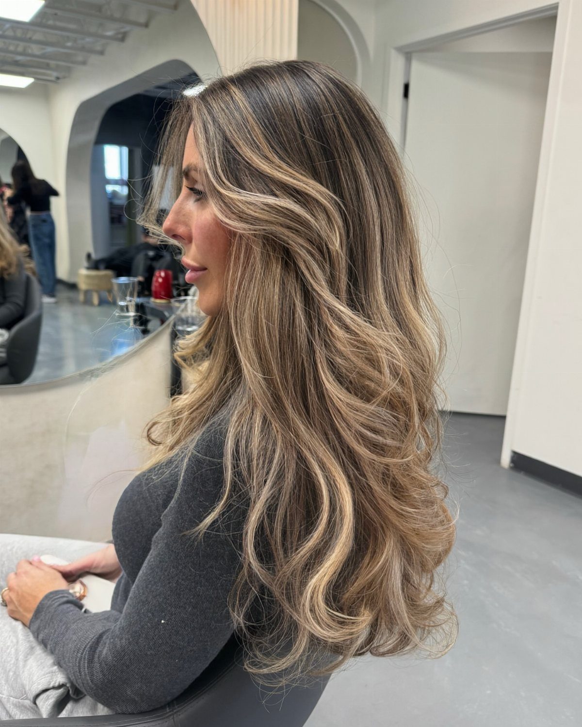 Long wavy brown hair with blended blonde balayage highlights in a salon