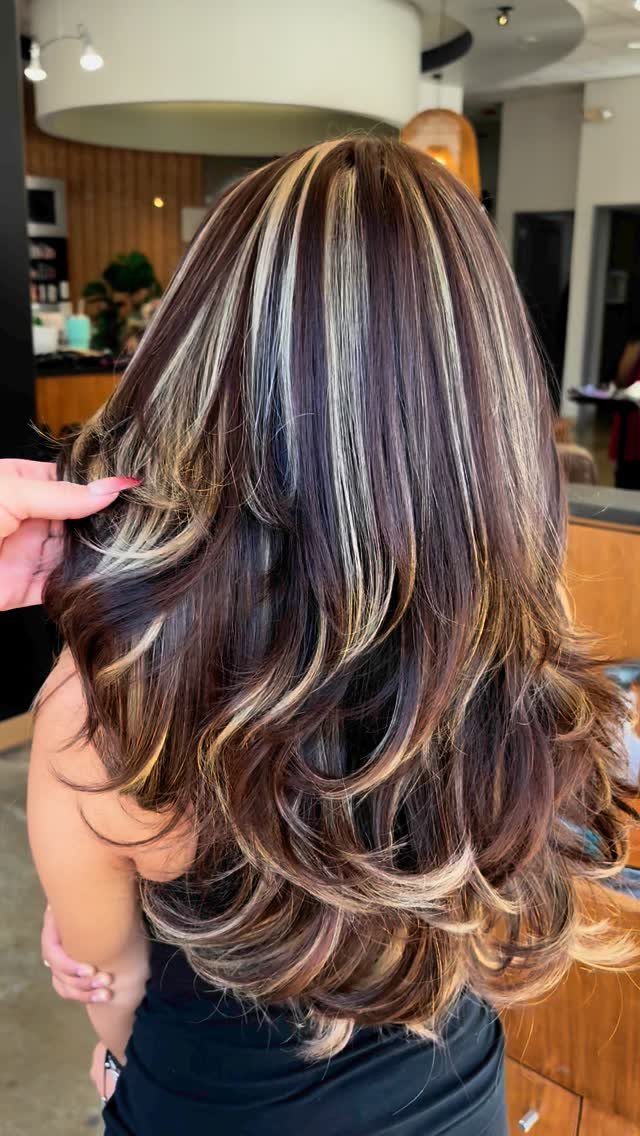 Long brown hair with chunky blonde highlights styled in layered salon curls