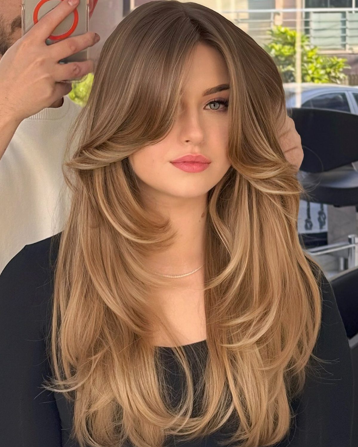 Long layered brown hair with fine blonde highlights styled in soft curls