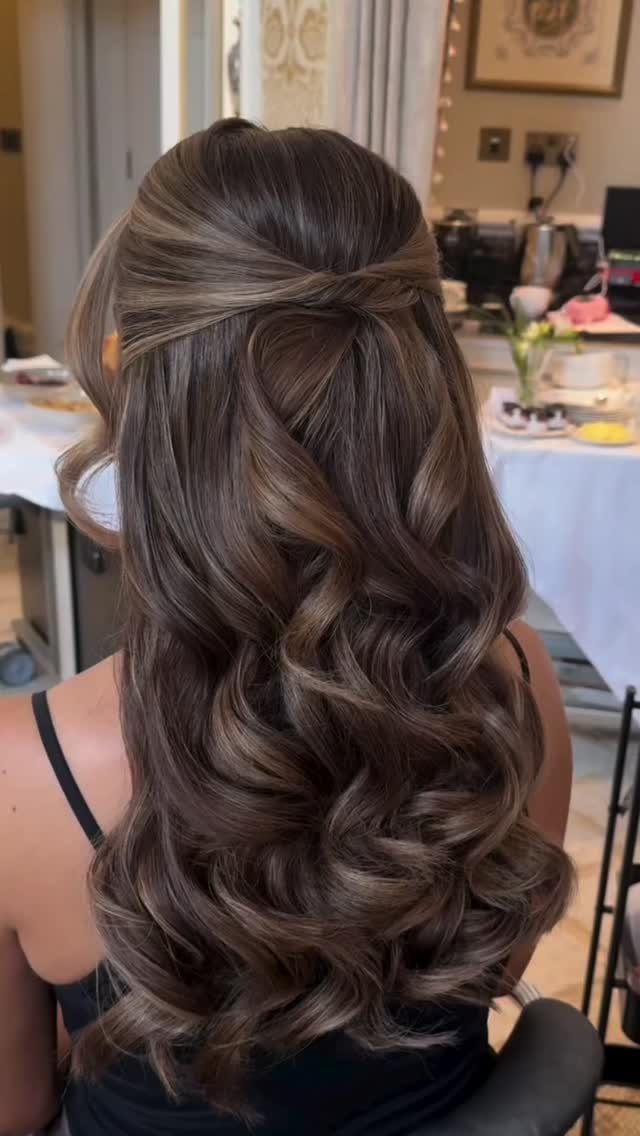 Long brown hair with blonde highlights styled half-up in loose curls