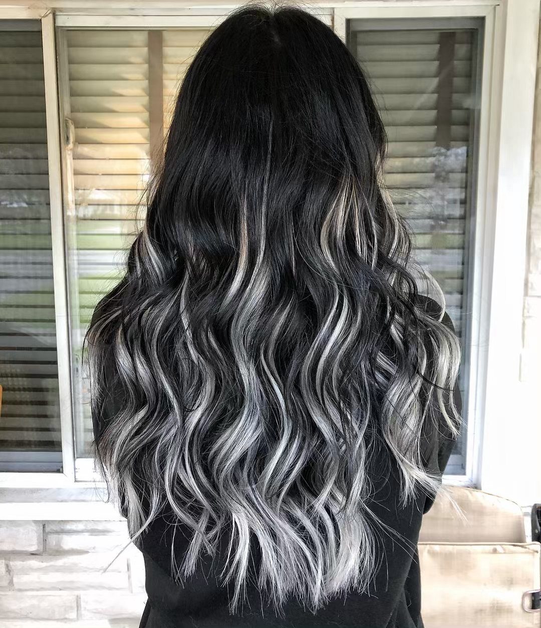 Wavy black hair with silver ash tones fading toward the ends