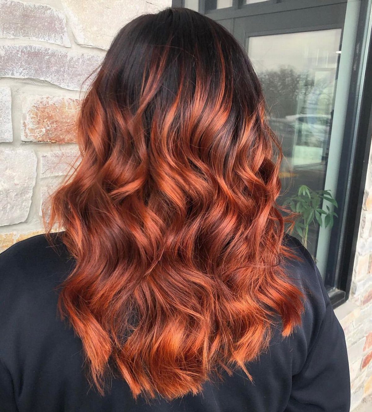 Wavy dark brown hair transitions into vivid copper auburn lengths and ends