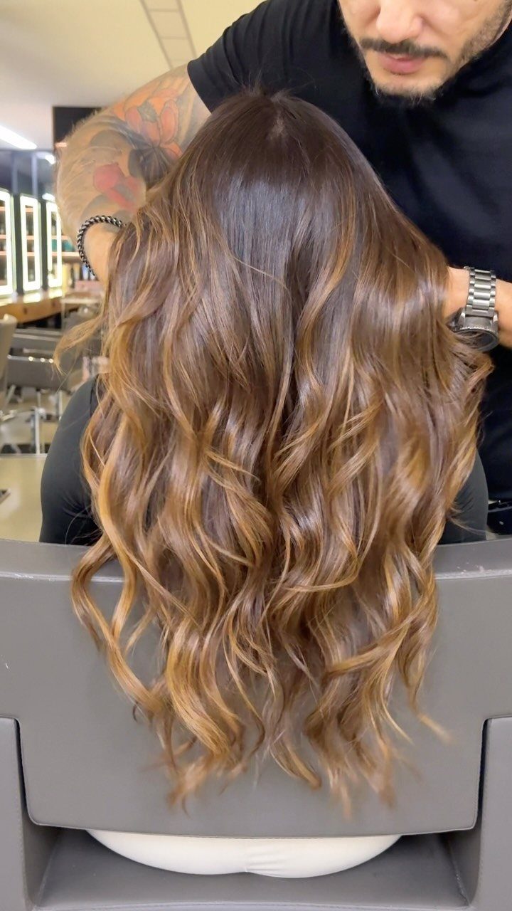 Long curled brown hair shows a warm brown-to-beige gradient in a salon