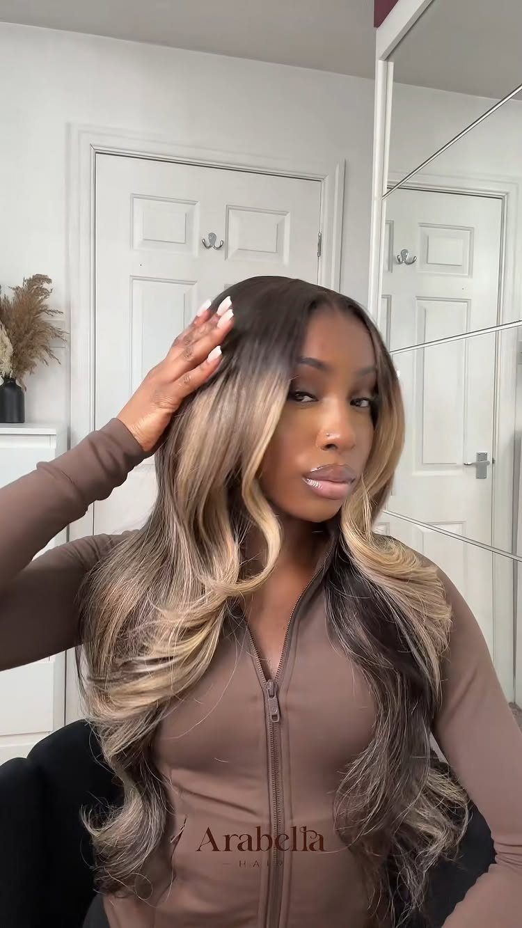 Woman showing long wavy hair with brown roots fading into blonde ends