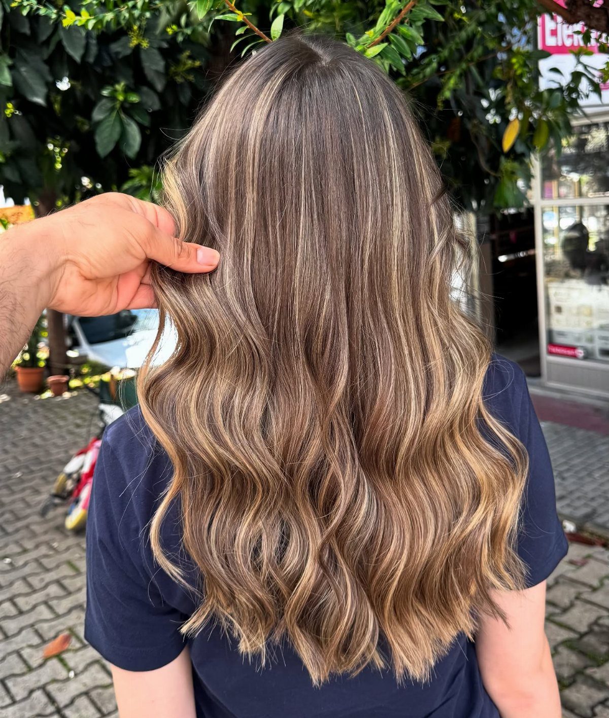 Wavy brown hair with caramel highlights cascading down a navy shirt