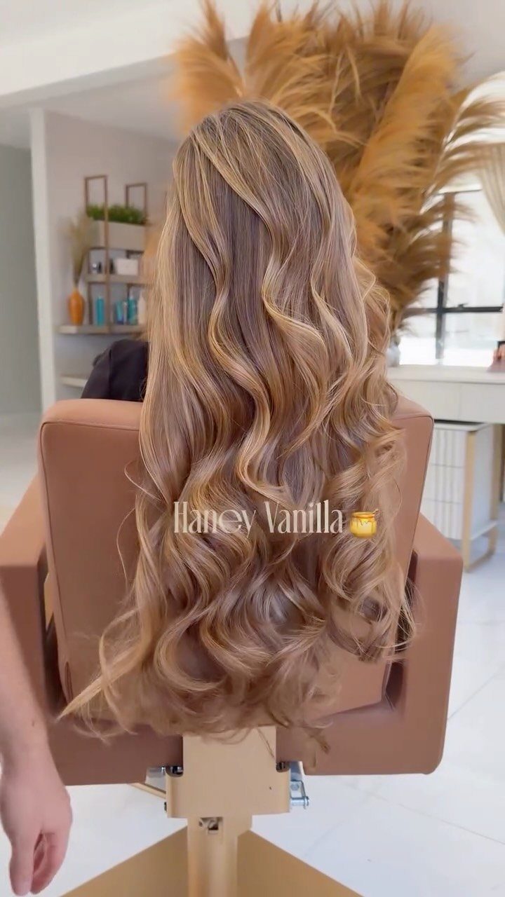 Wavy brunette hair blends into long honey-blonde ends in a salon