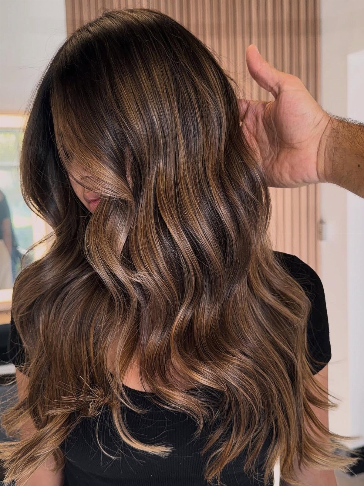 Long brunette waves show subtle lighter pieces through the ends
