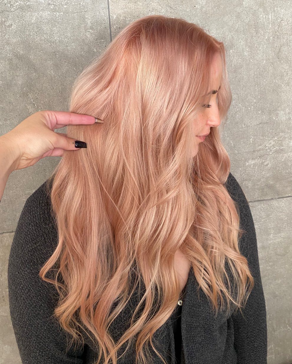 Long peach-strawberry hair with reddish roots falling in loose waves