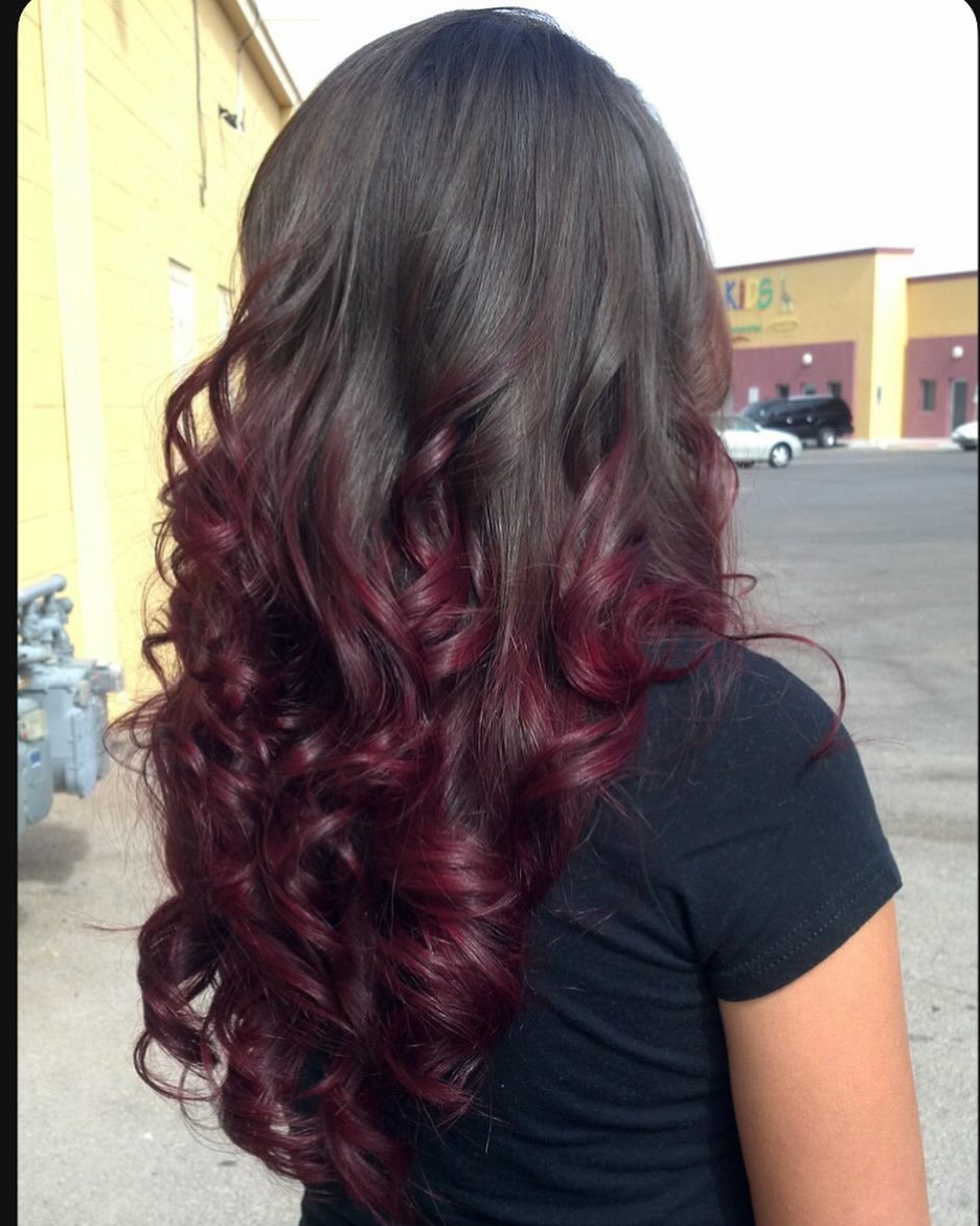 Long dark brown curls transition into deep burgundy-red ombre ends