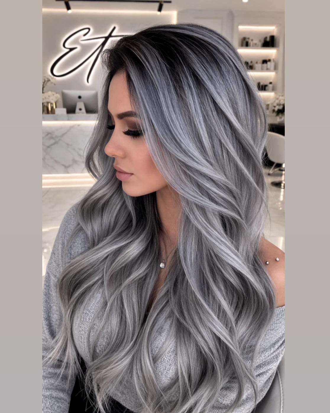 Woman with long silver-gray waves and lighter highlights in a salon