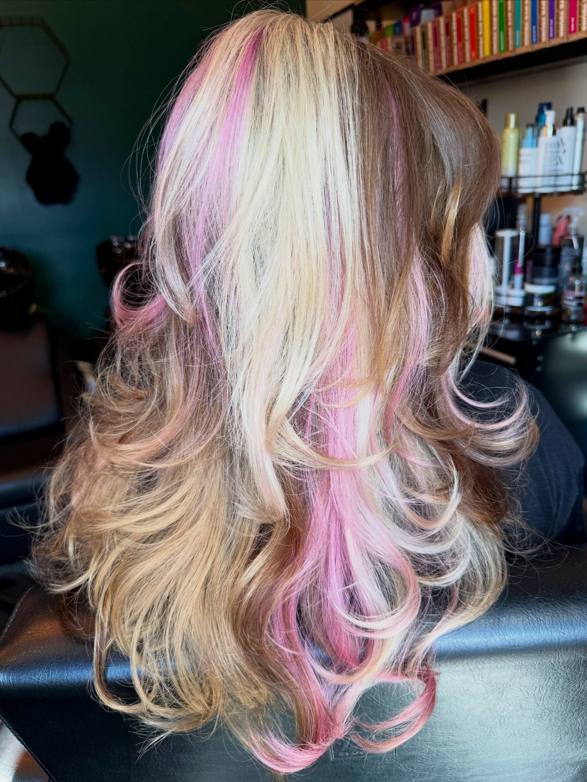 Layered blonde and brown hair with bright pink highlights curled at the ends