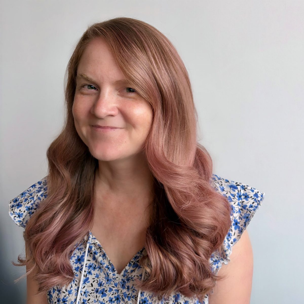Woman with long wavy brown hair blending into dusty rose lengths