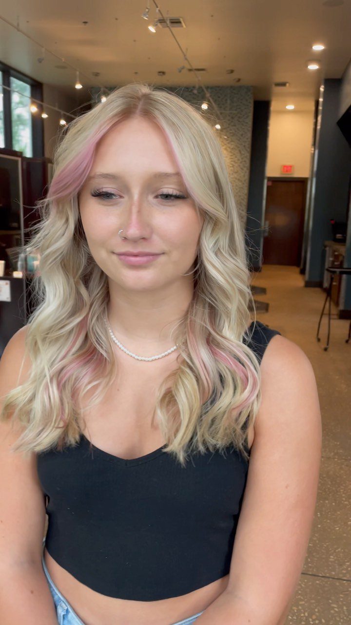 Woman with curled dirty-blonde hair featuring delicate pastel-pink highlights