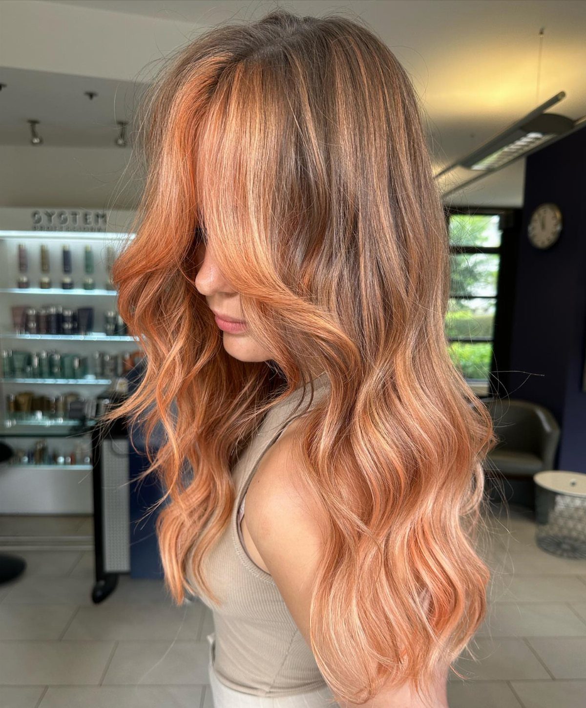 Woman with wavy brown hair and peachy-pink streaks framing her face