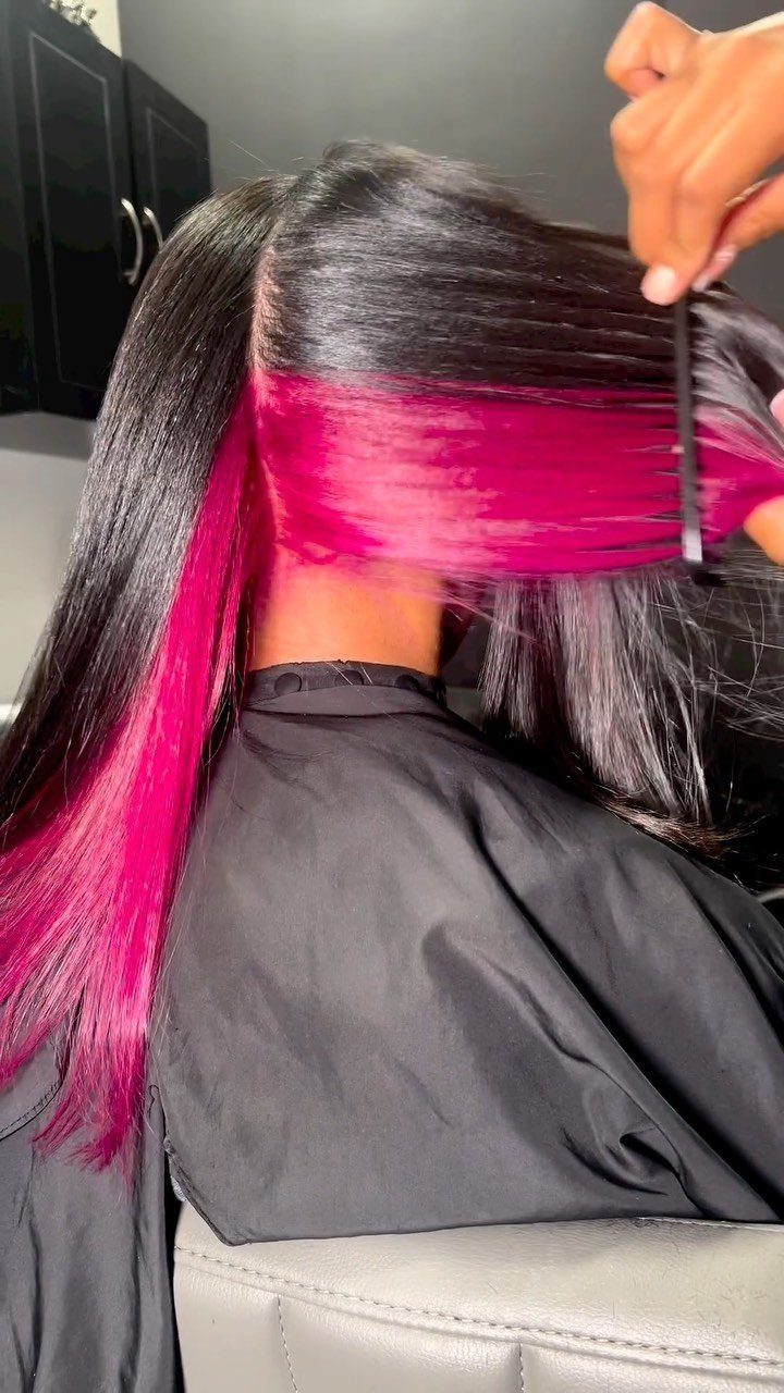 Black hair is lifted to reveal vivid pink peekaboo highlights underneath