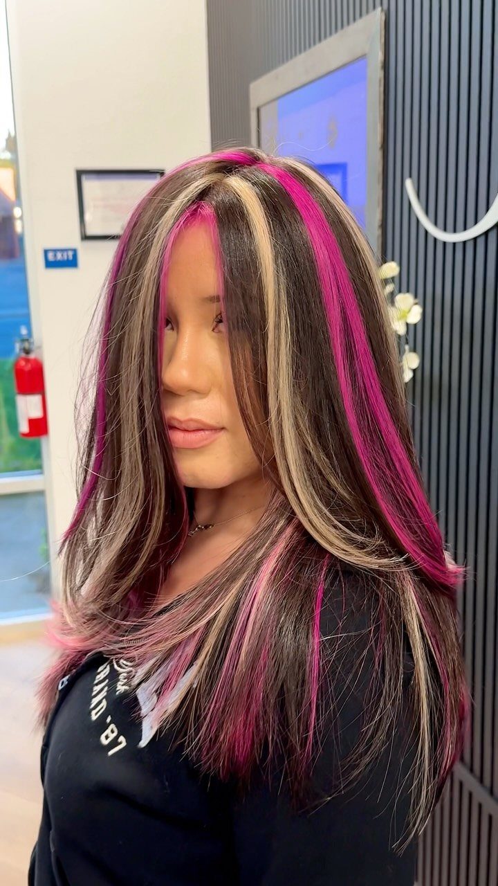Woman showing long dark hair with vivid pink and blonde highlights