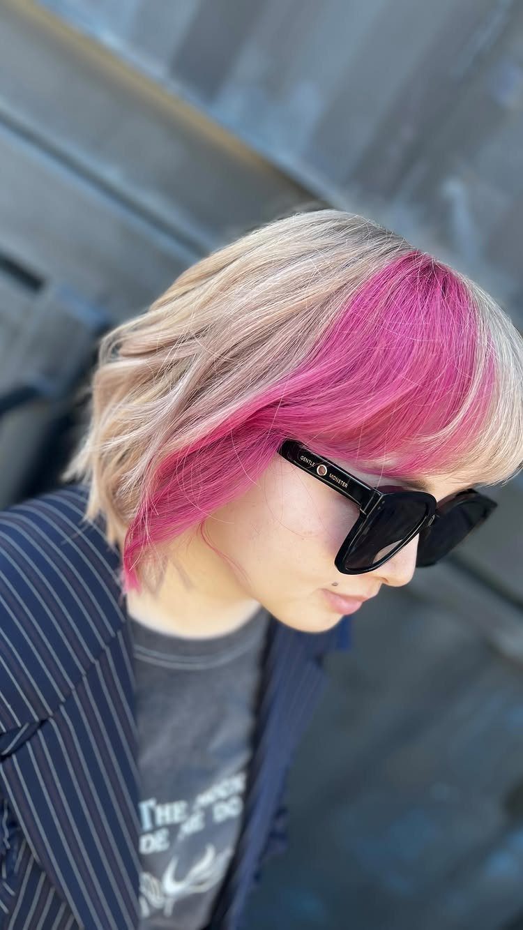 Short blonde bob with vivid pink top layers and black sunglasses