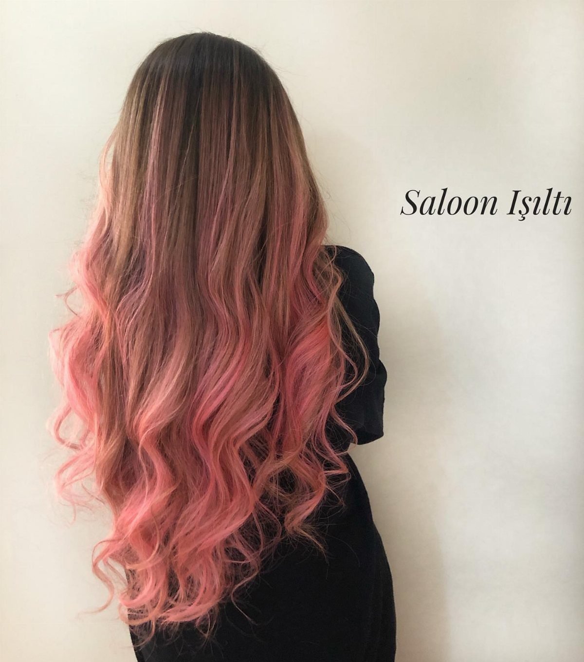 Long wavy hair fades from dark brown roots into salmon-pink ends