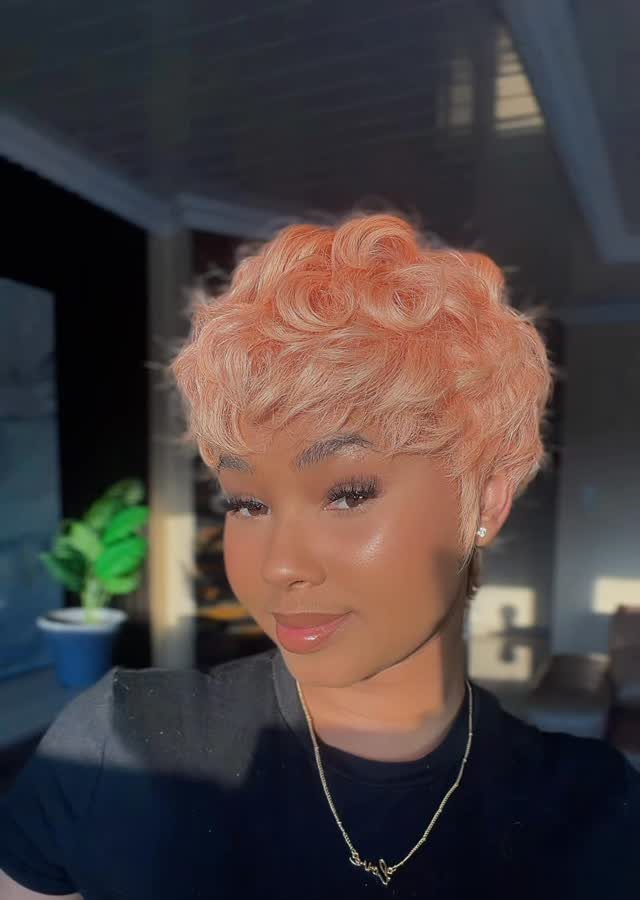 Person with a short coral pixie cut and softly curled hair