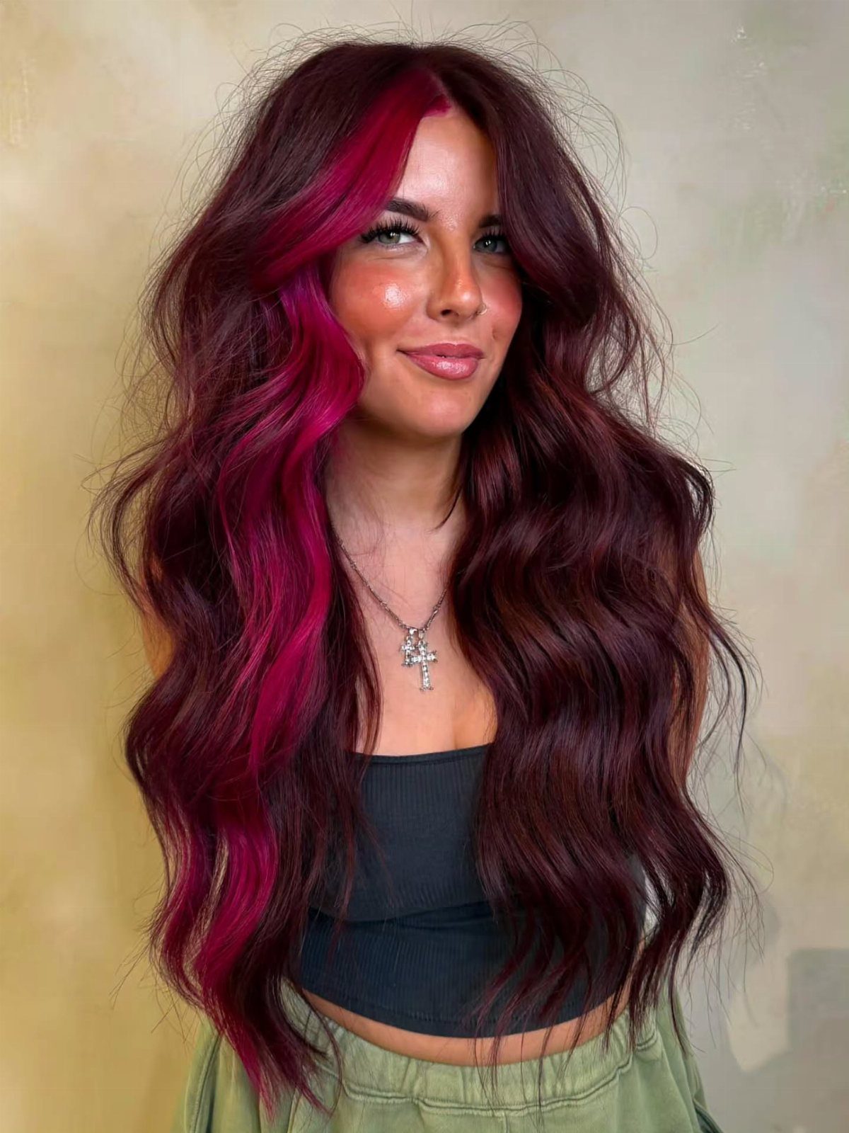 Woman with long dark waves and vivid magenta face-framing highlights