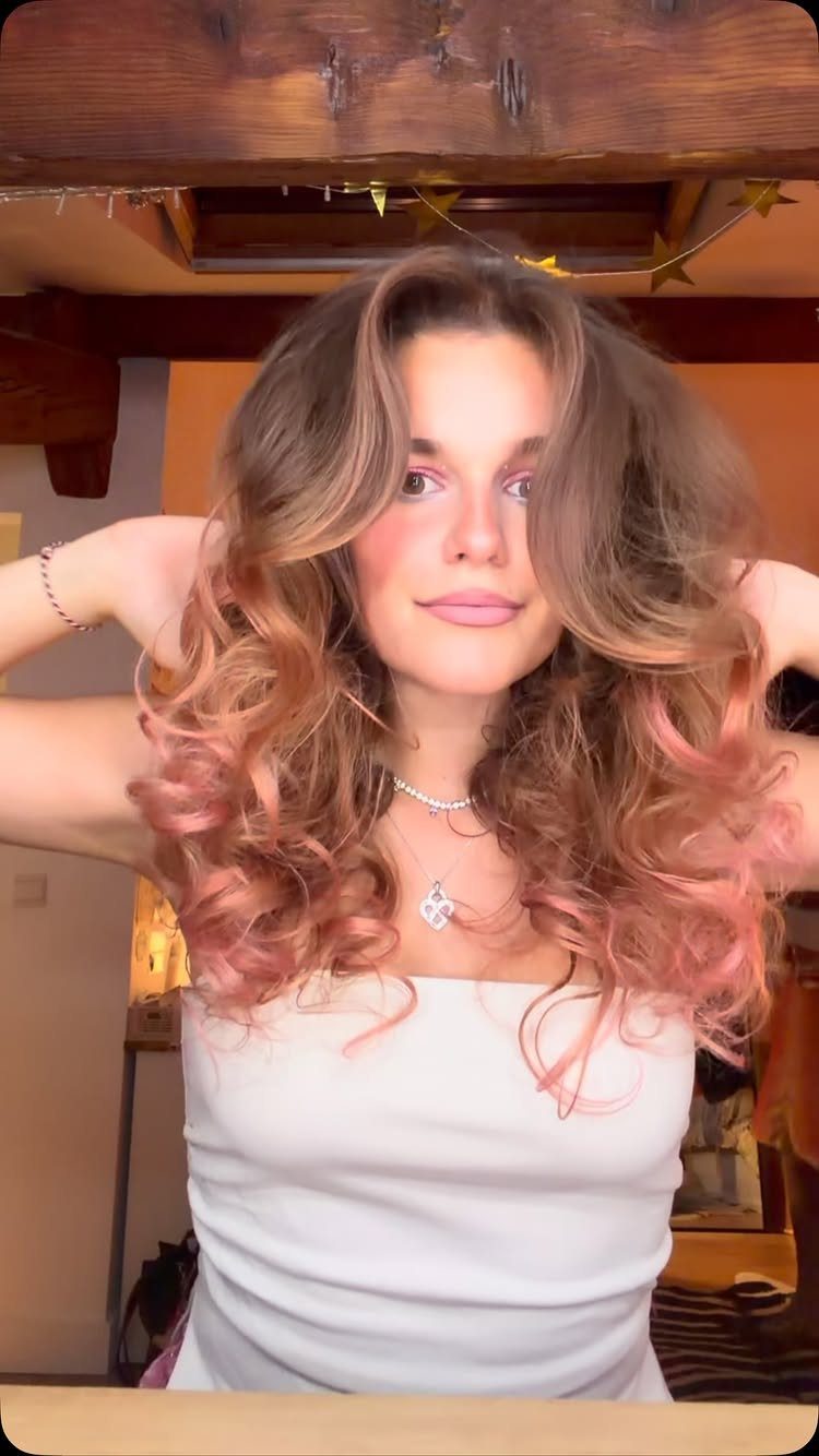 Woman displaying brunette waves blended into peachy rose-pink lengths
