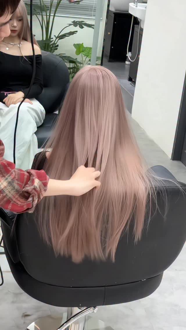Long pale pink hair with subtle highlights falls down a salon client’s back