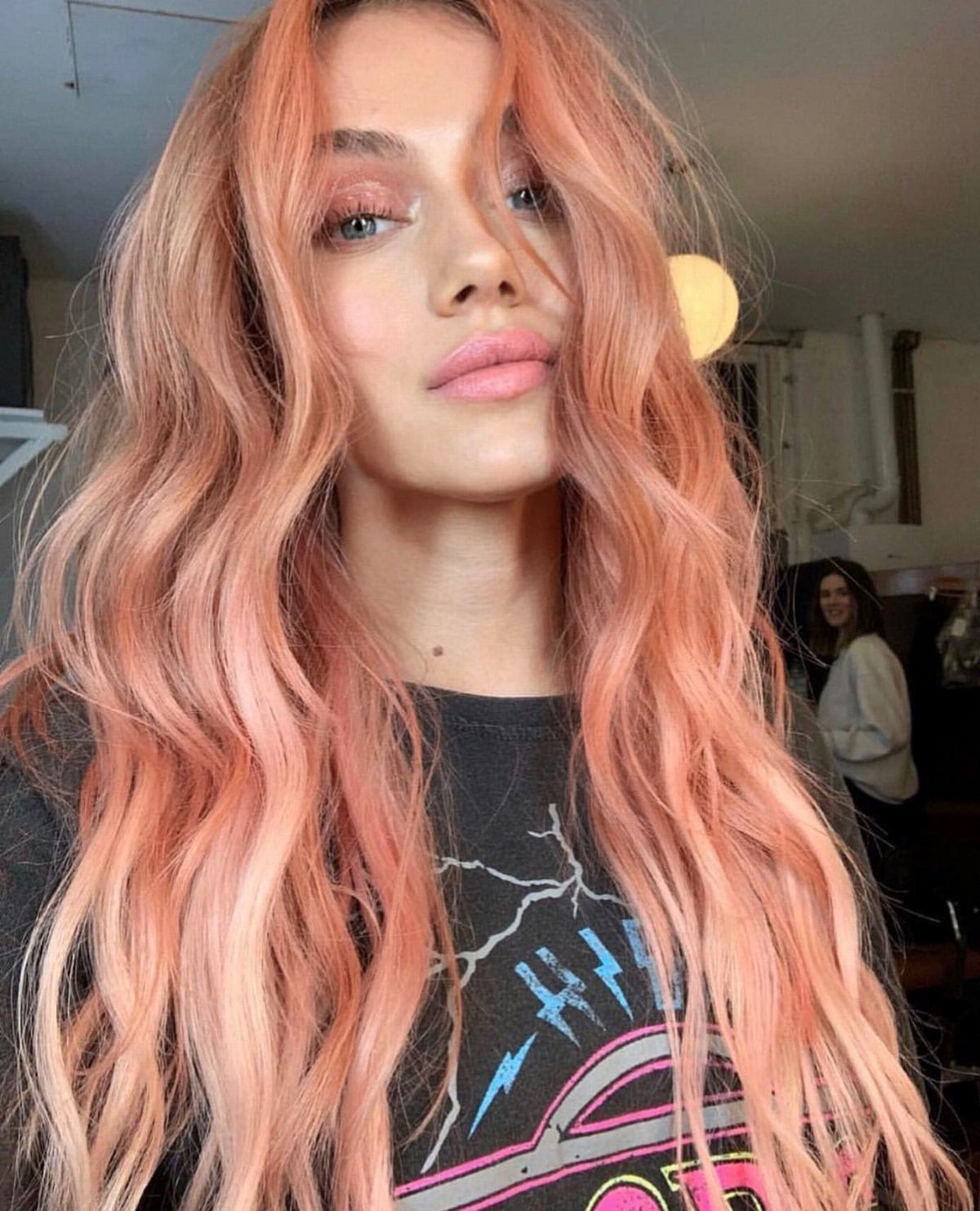 Woman with long, wavy peach-coral hair and lighter blonde-pink strands
