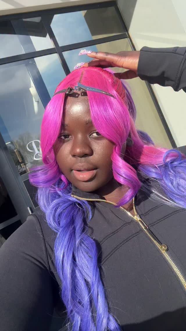 Person showing vivid pink hair at the crown blending into long purple-blue curls